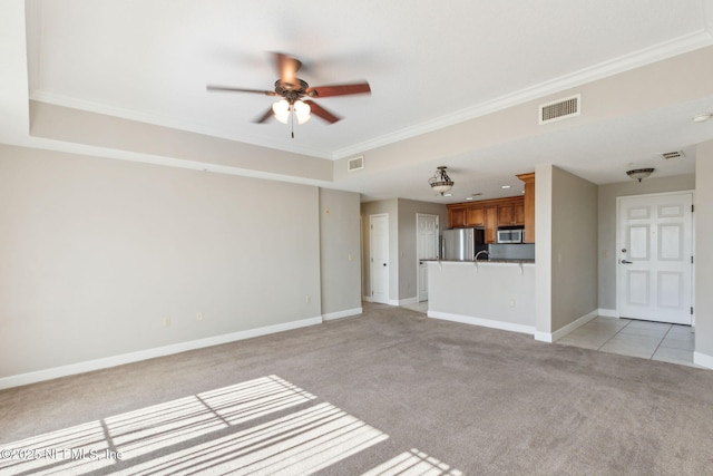 unfurnished living room with crown molding, baseboards, light colored carpet, visible vents, and ceiling fan