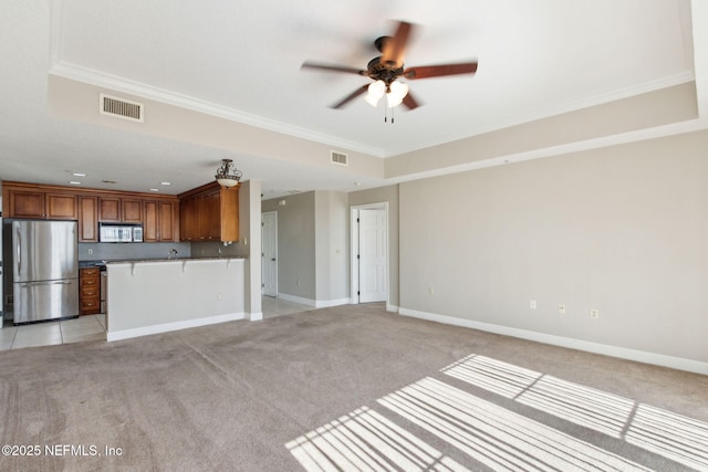 unfurnished living room with ceiling fan, visible vents, ornamental molding, and light carpet