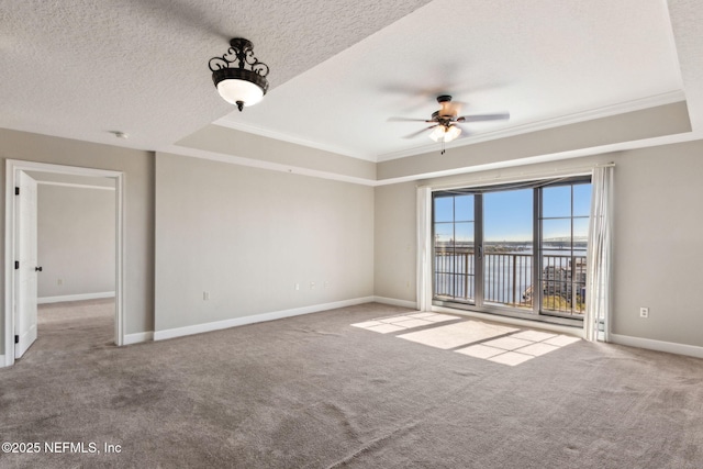 carpeted spare room featuring baseboards, a ceiling fan, a textured ceiling, and a raised ceiling