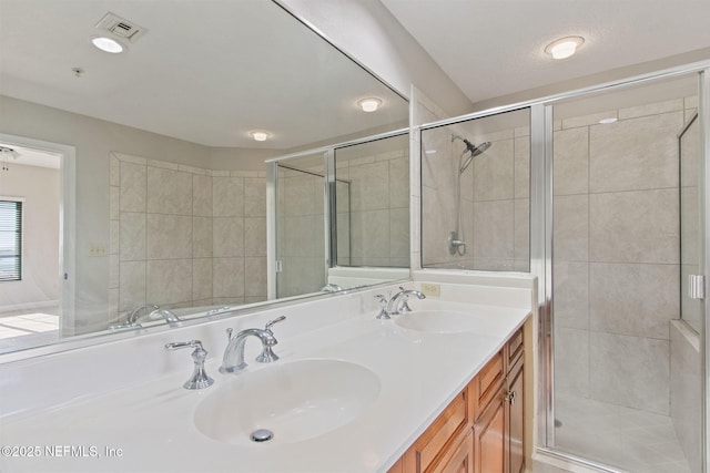 full bath featuring visible vents, a sink, double vanity, and a shower stall