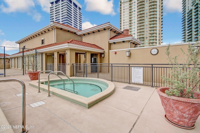 view of swimming pool with fence and a hot tub