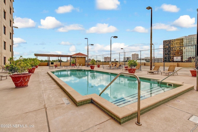 community pool with a pergola, fence, and a patio