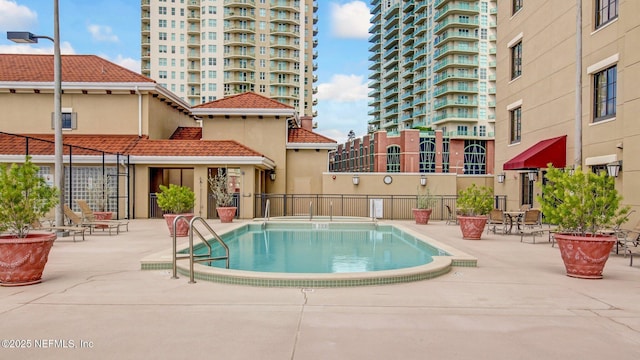 community pool featuring fence and a patio