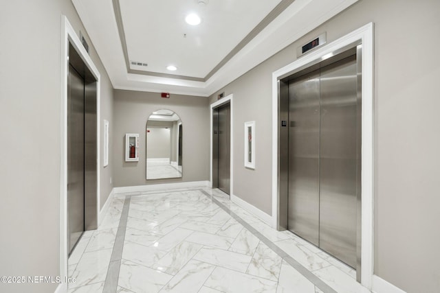 corridor with marble finish floor, elevator, recessed lighting, and a tray ceiling