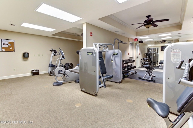 exercise room with baseboards, ceiling fan, ornamental molding, a raised ceiling, and carpet floors
