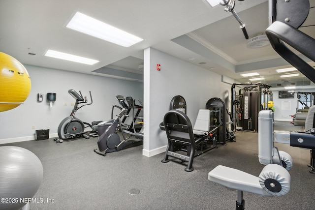 gym with crown molding, baseboards, and a tray ceiling