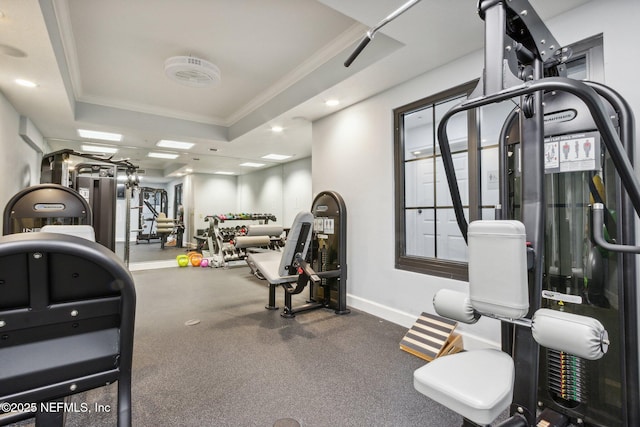 gym with ornamental molding, a tray ceiling, baseboards, and recessed lighting