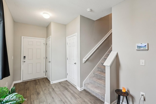7802 Merchants Way, Jacksonville, FL 32222 - foyer entrance featuring a textured ceiling, baseboards, wood finished floors, and stairs