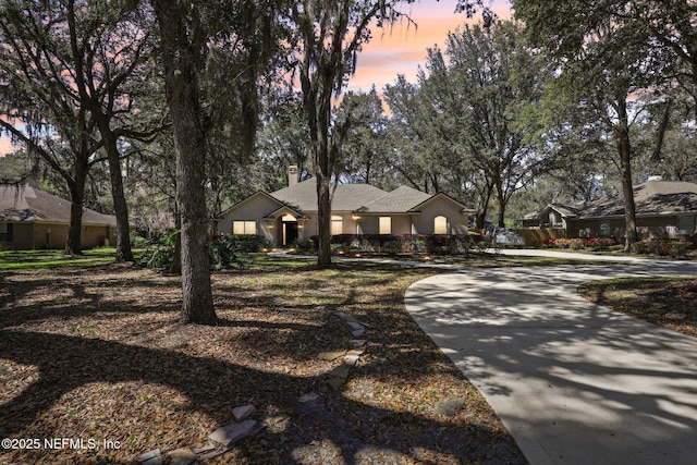 view of front of house featuring concrete driveway, stucco siding, and a chimney