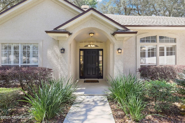 property entrance featuring stucco siding and roof with shingles