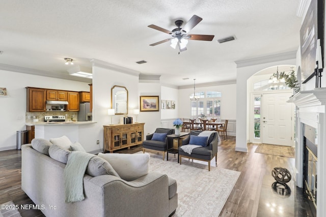 living area with visible vents, crown molding, and wood finished floors