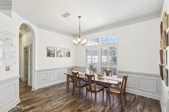 dining room with dark wood-style flooring, visible vents, arched walkways, and a textured ceiling