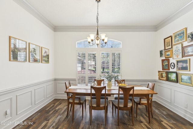 dining area featuring dark wood-style flooring, a textured ceiling, crown molding, and a notable chandelier