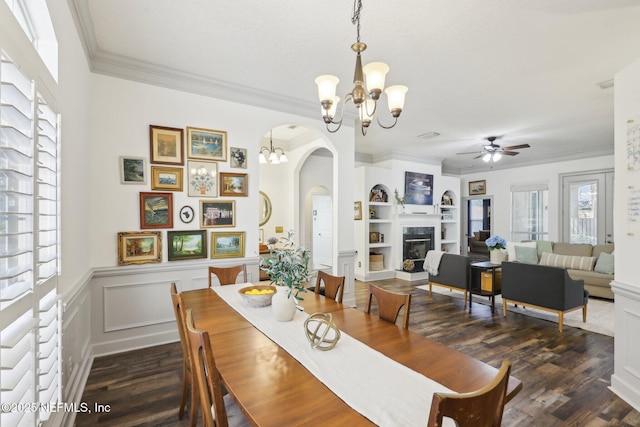 dining area featuring ornamental molding, ceiling fan with notable chandelier, arched walkways, and built in shelves