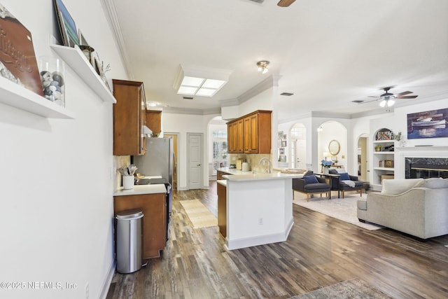 kitchen featuring arched walkways, brown cabinetry, and ceiling fan