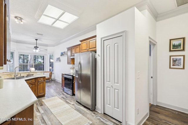 kitchen featuring ornamental molding, stainless steel appliances, brown cabinetry, and light wood finished floors