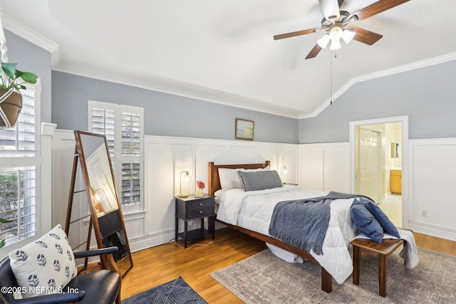 bedroom featuring a wainscoted wall, vaulted ceiling, wood finished floors, and ornamental molding