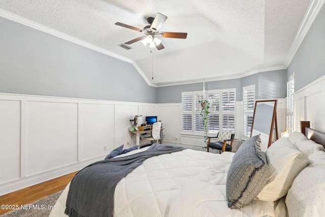 bedroom featuring visible vents, wood finished floors, lofted ceiling, and a textured ceiling