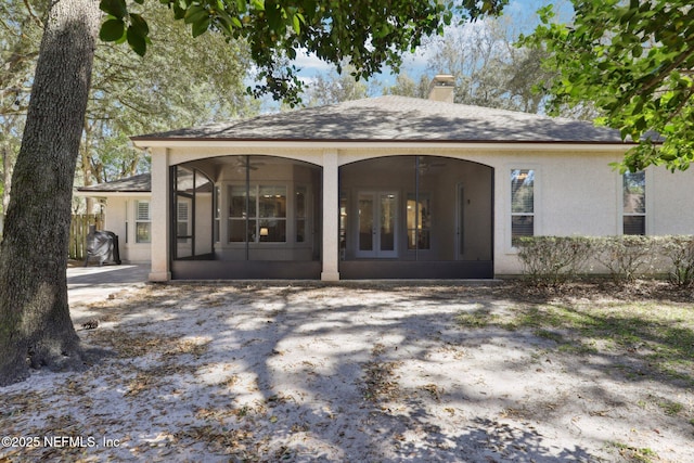 rear view of property featuring a chimney, ceiling fan, french doors, and roof with shingles