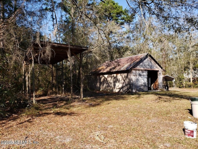 view of outdoor structure with an outbuilding, a view of trees, and a carport