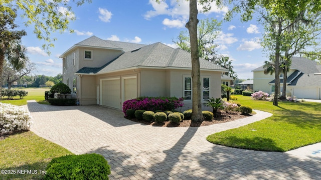 1193 Queens Harbor Blvd, Jacksonville, FL 32225 - view of side of home featuring stucco siding, decorative driveway, a garage, a yard, and a shingled roof
