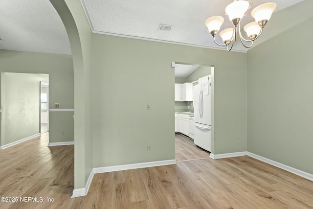 7552 Pottsburg Landing Dr, Jacksonville, FL 32216 - unfurnished dining area featuring baseboards, arched walkways, light wood-style floors, and an inviting chandelier