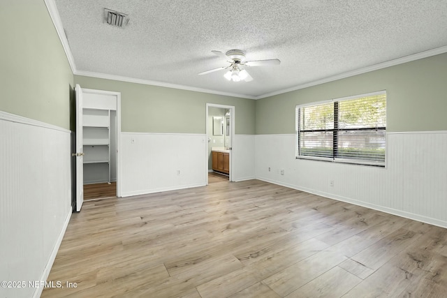 7552 Pottsburg Landing Dr, Jacksonville, FL 32216 - empty room with a ceiling fan, light wood finished floors, a textured ceiling, wainscoting, and visible vents