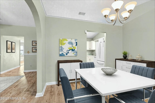 7552 Pottsburg Landing Dr, Jacksonville, FL 32216 - dining space with visible vents, baseboards, arched walkways, light wood-style floors, and a notable chandelier