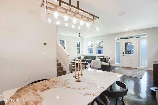kitchen with finished concrete flooring, baseboards, ceiling fan, and a kitchen breakfast bar