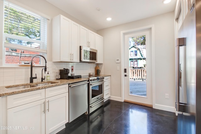 kitchen featuring decorative backsplash, a sink, light stone counters, and appliances with stainless steel finishes