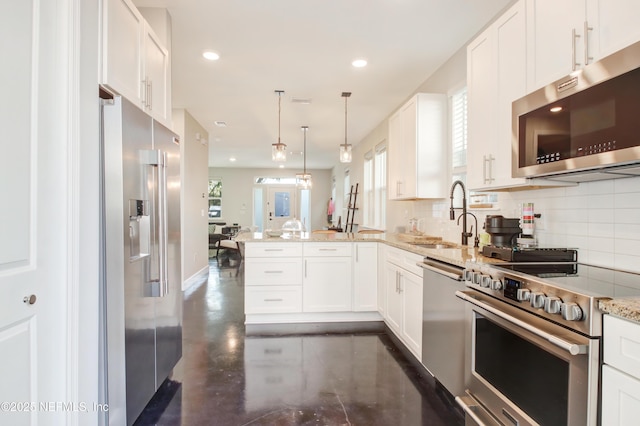 kitchen with a sink, tasteful backsplash, a peninsula, and appliances with stainless steel finishes
