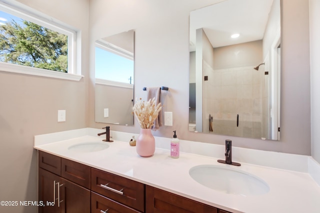 bathroom featuring double vanity, a sink, and tiled shower
