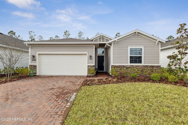 75586 Pondside Ln, Yulee, FL 32097 - view of front of house featuring stone siding, a front yard, decorative driveway, and an attached garage