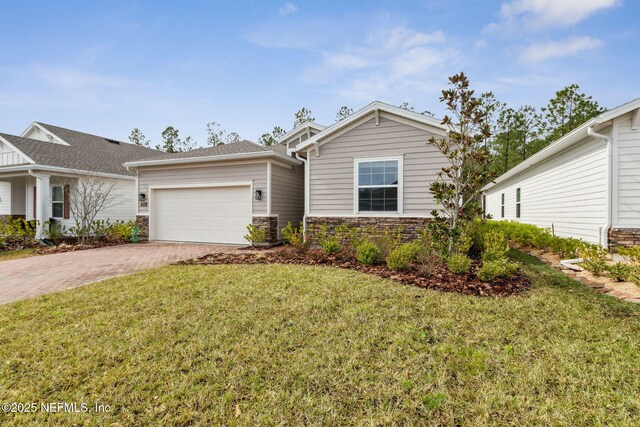 75586 Pondside Ln, Yulee, FL 32097 - view of front of house with a front lawn, decorative driveway, stone siding, and a garage