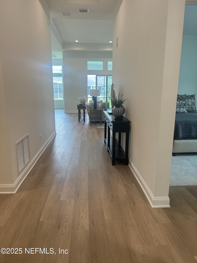 hall with baseboards, visible vents, and wood finished floors