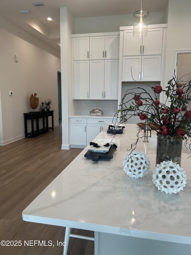 kitchen with white cabinetry, baseboards, tasteful backsplash, and wood finished floors