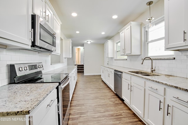 10568 Lake View Rd E, Jacksonville, FL 32225 - kitchen featuring light stone countertops, appliances with stainless steel finishes, white cabinetry, a sink, and light wood-type flooring