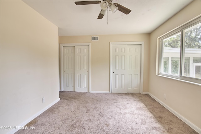 10568 Lake View Rd E, Jacksonville, FL 32225 - unfurnished bedroom with two closets, carpet, baseboards, visible vents, and a ceiling fan