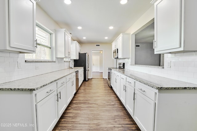 10568 Lake View Rd E, Jacksonville, FL 32225 - kitchen featuring white cabinetry, recessed lighting, a sink, appliances with stainless steel finishes, and wood finished floors