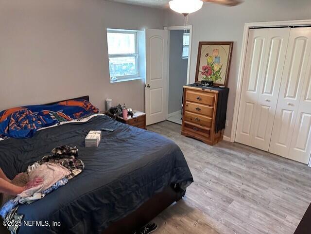 bedroom featuring baseboards, a ceiling fan, wood finished floors, and a closet