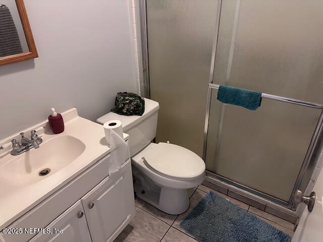 bathroom with a shower stall, tile patterned flooring, vanity, and toilet