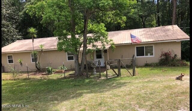 back of property featuring a lawn, metal roof, and stucco siding