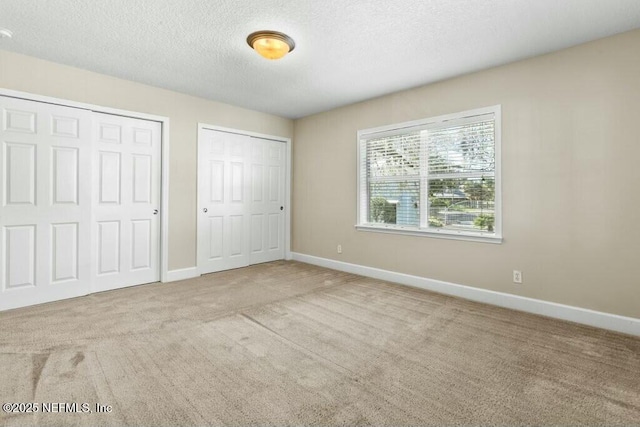3434 Blanding Blvd Unit 201, Jacksonville, FL 32210 - unfurnished bedroom featuring baseboards, a textured ceiling, carpet, and two closets