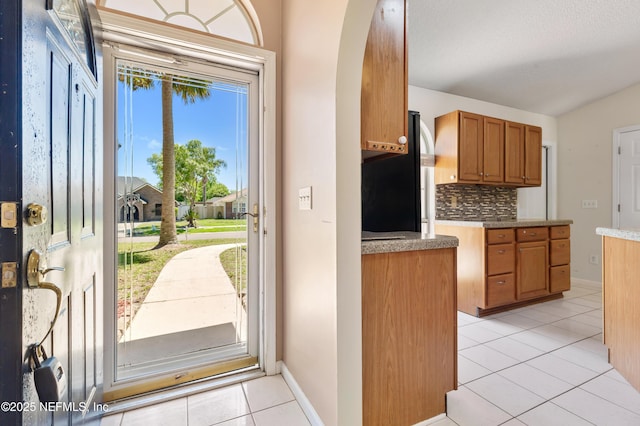 3387 Guernsey Ct, Jacksonville, FL 32226 - interior space with light tile patterned flooring, freestanding refrigerator, baseboards, decorative backsplash, and brown cabinetry