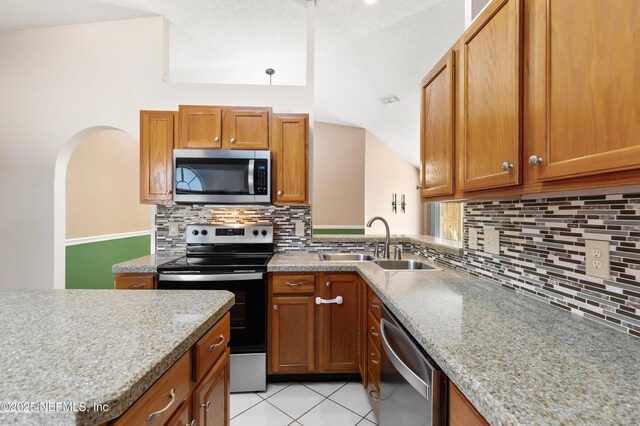 3387 Guernsey Ct, Jacksonville, FL 32226 - kitchen with a sink, brown cabinetry, decorative backsplash, light tile patterned floors, and stainless steel appliances