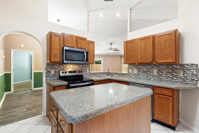 3387 Guernsey Ct, Jacksonville, FL 32226 - kitchen featuring stainless steel appliances, a sink, tasteful backsplash, ceiling fan, and brown cabinetry