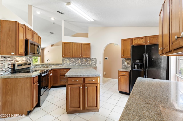 3387 Guernsey Ct, Jacksonville, FL 32226 - kitchen with arched walkways, stainless steel microwave, tasteful backsplash, vaulted ceiling, and electric range oven