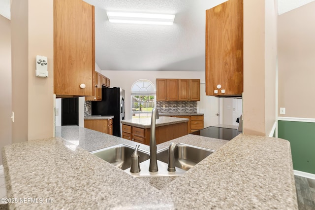 3387 Guernsey Ct, Jacksonville, FL 32226 - kitchen featuring a textured ceiling, a sink, tasteful backsplash, brown cabinets, and light countertops