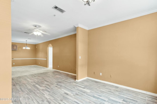 unfurnished room featuring visible vents, baseboards, ornamental molding, arched walkways, and light wood-type flooring