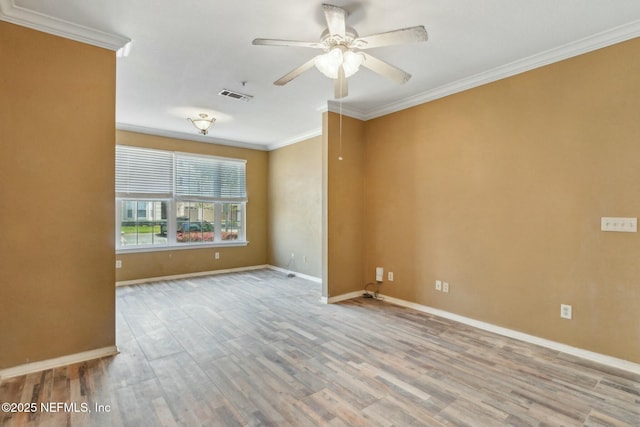 unfurnished room featuring crown molding, baseboards, visible vents, a ceiling fan, and wood finished floors